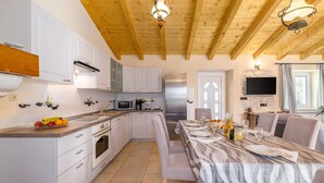 Une cuisine moderne avec des meubles blancs, un réfrigérateur en acier inoxydable et un coin repas avec une table dressée pour quatre personnes.