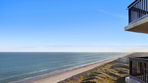Een kustgezicht vanaf een balkon met uitzicht op een strand en de oceaan.