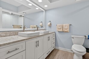 A bathroom with two sinks, a toilet, and a large mirror. - Sandpiper Condominiums 1105T, Panoramic Gulf View w/ direct access to Mustang Island/Port A beaches. (Port Aransas)