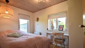 Ein Schlafzimmer mit Bett, Stuhl, Schreibtisch und Fenster.