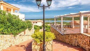 Un escalier en pierre mène à une terrasse d’où l’on a une vue sur la mer et les maisons.
