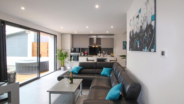A modern living room with a black leather sofa, a coffee table, and a dining area in the background. - Beautiful home in Salon de Provence (Salon de Provence)