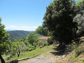 A rural landscape with a stone building, trees, and a clear sky.