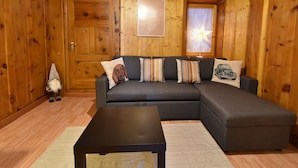 Una sala acogedora con un sofá modular, una mesita y piso de madera.