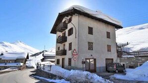 Un edificio de dos pisos con tejado cubierto de nieve y una señal de límite de velocidad de 30.