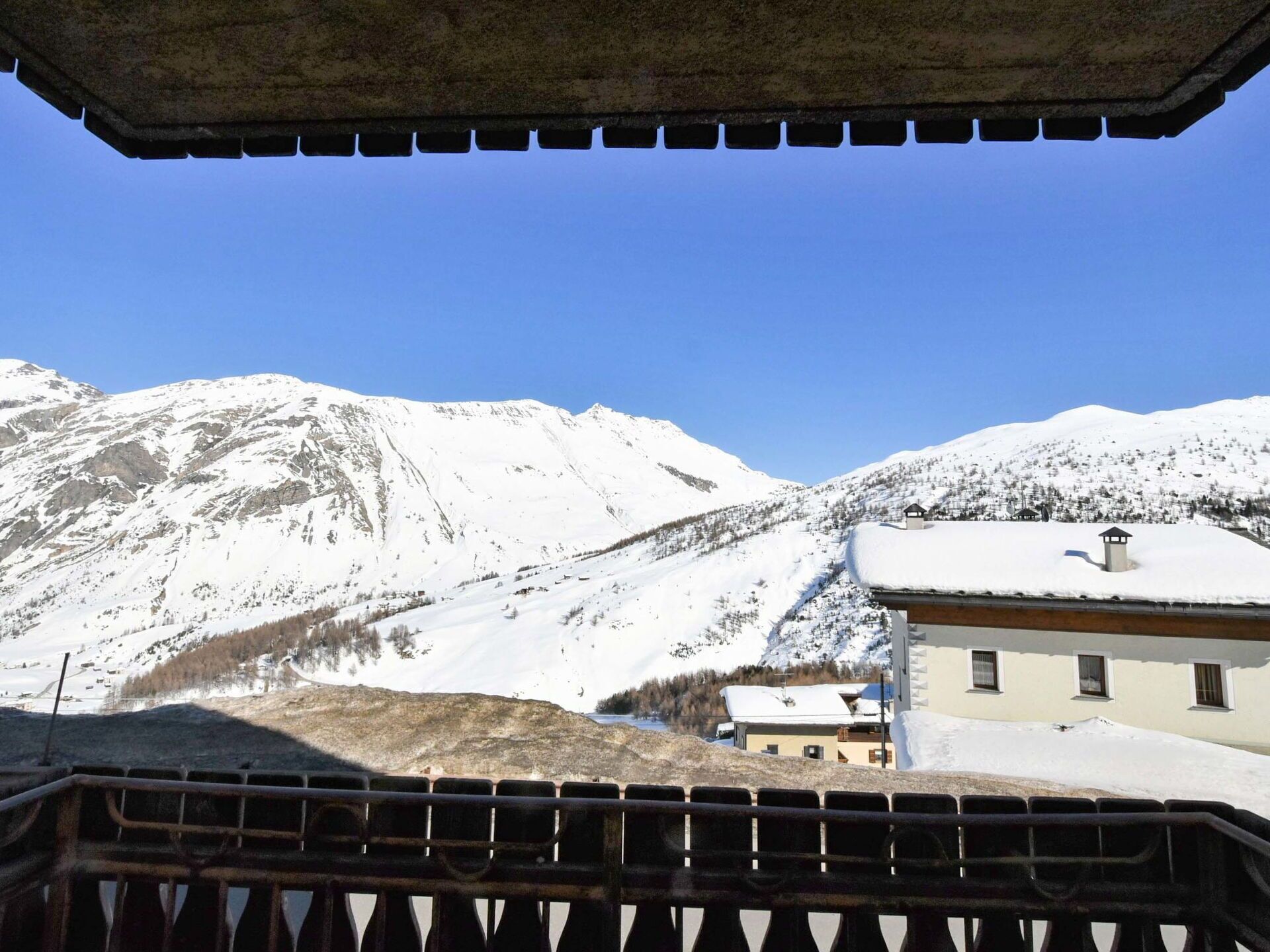 A mountain landscape with snow-covered peaks and a building with a sloped roof.