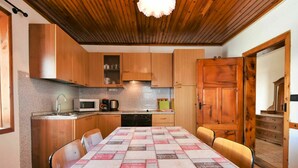 Una cocina acogedora con armarios de madera, una mesa de comedor con mantel a cuadros y techo de madera.