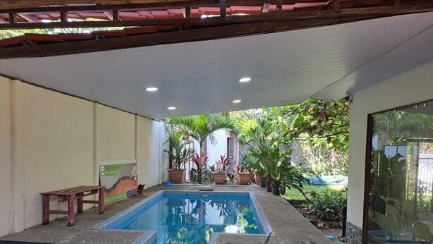 A swimming pool with a bench and potted plants around it.