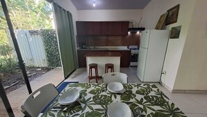 A compact kitchen with wooden cabinets, a white refrigerator, and a dining area with a table set for four.