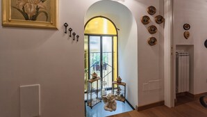A hallway with a large arched doorway, a framed painting, wall-mounted keys, decorative lanterns, and a radiator. - La Casa degli Angeli B&B (Salerno)