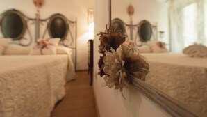 A bedroom with two beds, a mirror, and a floral decoration on the wall. - La Casa degli Angeli B&B (Salerno)