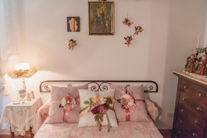 Une chambre à coucher comprenant un lit, une table de chevet, une commode et des éléments de décoration murale, notamment un tableau encadré et des figurines.