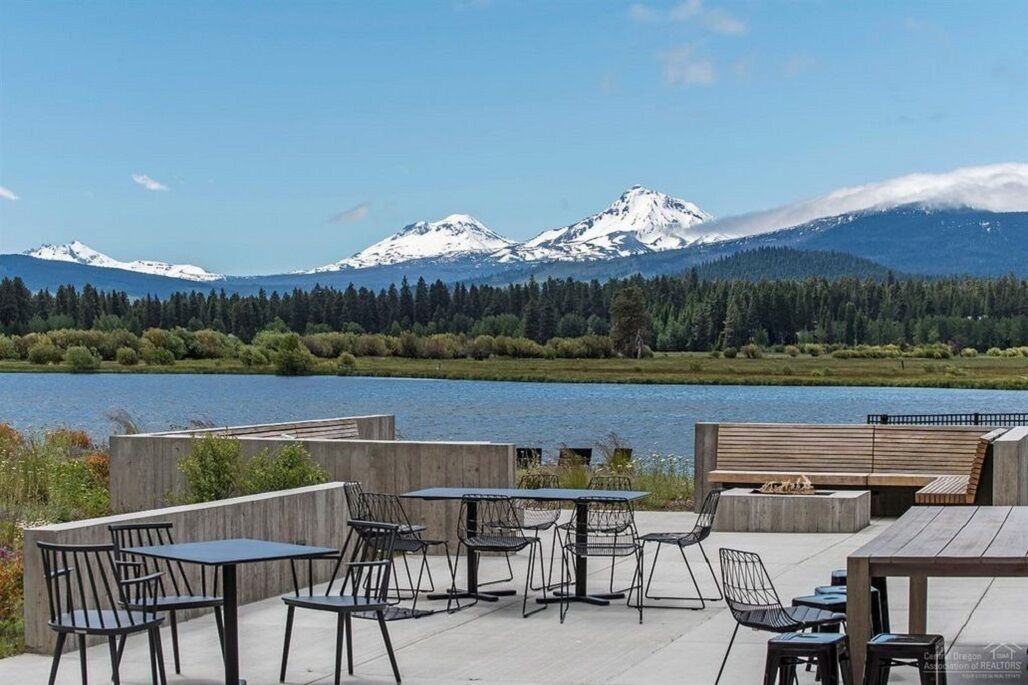 An outdoor seating area with tables and chairs overlooking a lake and mountains.