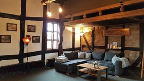 Habitación acogedora con vigas de madera a la vista, chimenea, sofá, mesa de centro y radiador.