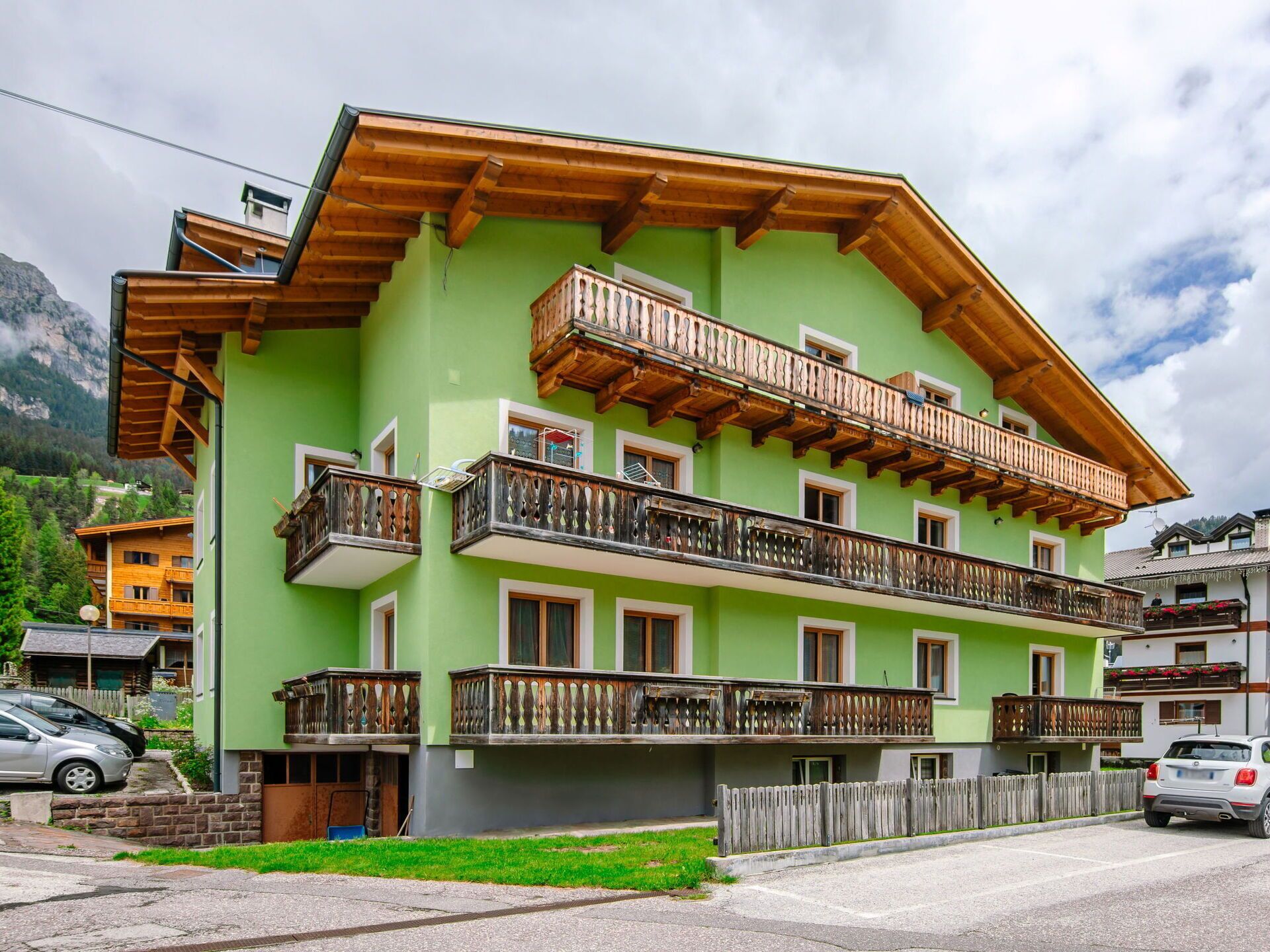 A multi-story building with wooden balconies and a green facade.