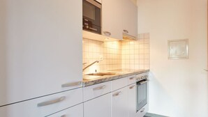 Et moderne køkken med hvide skabe, en granitbordplade og en indbygget ovn.