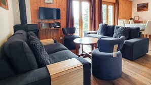 En moderne stue med mørke sofaer, et træbord og et fladskærms-tv monteret på væggen.