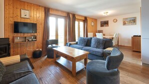 En hyggelig stue med trævægge, et fladskærms-tv, en sofasæt, et sofabord og en pejs.