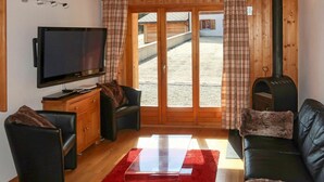 A cozy living room with a TV, leather sofas, a red rug, and a wood-burning stove. - Cosy apartment for 7 people with WIFI, TV and balcony (Les Collons)