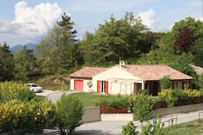 A house with a red roof, a garage, and a garden with yellow flowers.