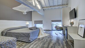 Een moderne slaapkamer met een groot bed, een bureau met een computer en een stoel.