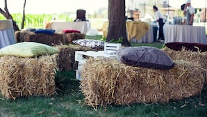 Heuballen mit Kissen auf einer Wiese, wahrscheinlich bei einer Outdoor-Veranstaltung oder einem Festival.