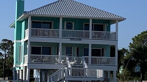 A two-story beachfront house with a balcony, a staircase, and a sandy beach in the foreground. - "No Pressure"  Beautiful beach front home (Port St Joe)