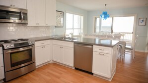 A modern kitchen with white cabinets, stainless steel appliances, and a wooden floor. - "No Pressure"  Beautiful beach front home (Port St Joe)