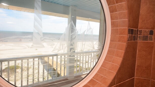 A circular window overlooking a beach with white sail-like structures. - "No Pressure"  Beautiful beach front home (Port St Joe)