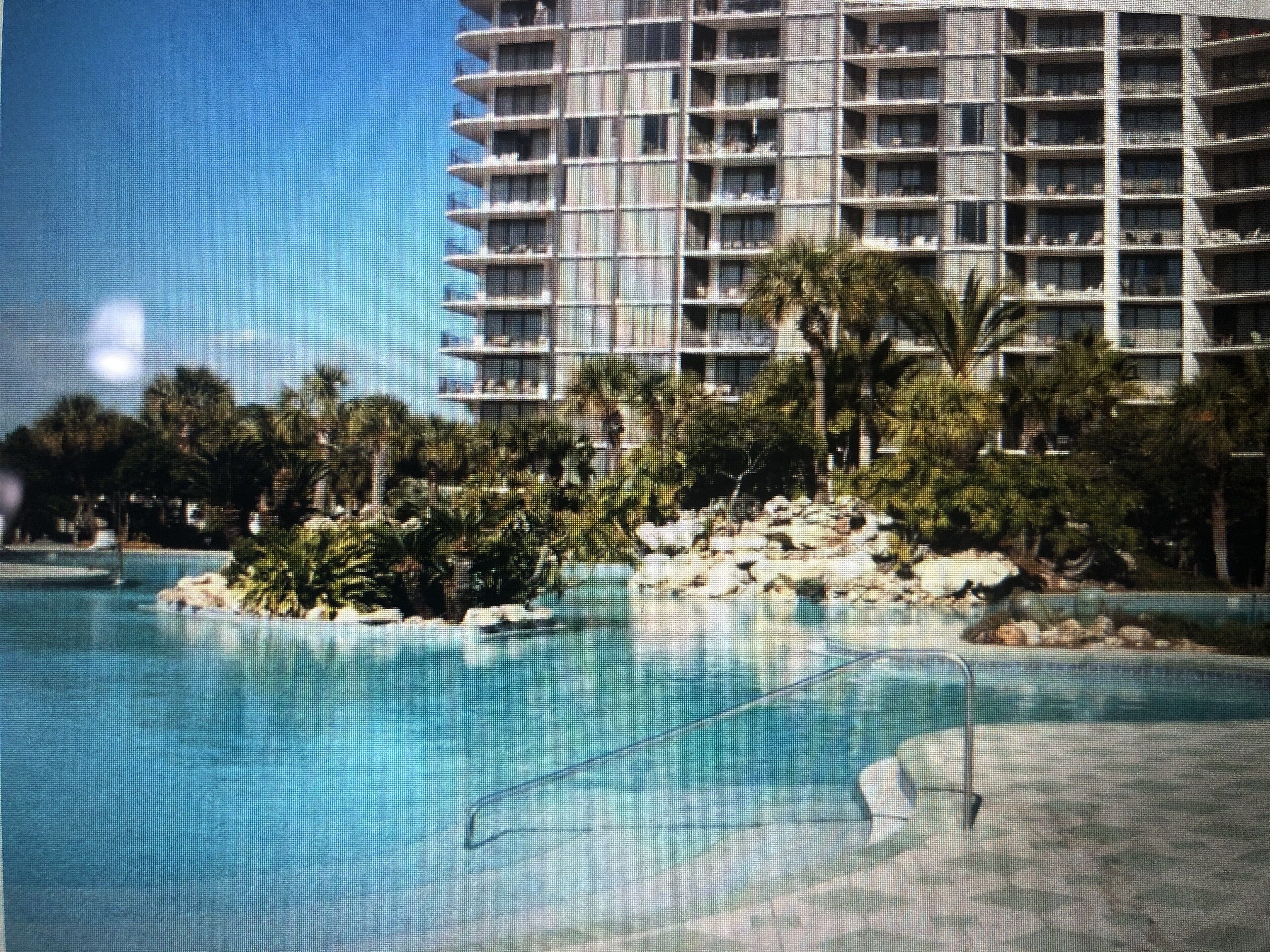 Un grand hôtel doté de nombreux balcons, d’une piscine et entouré de verdure.