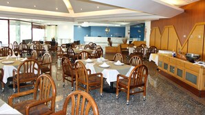 A spacious dining area with multiple tables and chairs, a reception desk, and a kitchen area. - Hotel San Juan Park (San Juan del Río)