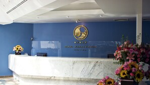 A reception desk at the San Juan Park Hotel with a blue wall and a logo above it. - Hotel San Juan Park (San Juan del Río)