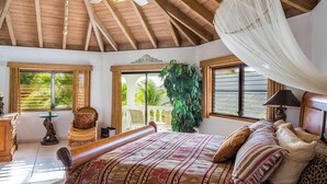 Une chambre spacieuse avec un grand lit, un ventilateur de plafond et une vue sur l’extérieur.