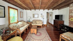 Ein gemütliches Wohnzimmer mit Holzbalkendecke, einer Couch, einem Couchtisch und einem Fernseher.