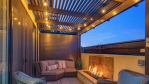 A covered patio area with a fire feature, wicker furniture, and a view of the night sky.