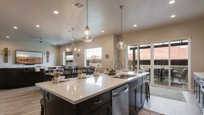 A modern kitchen with a large island, dark cabinetry, and pendant lighting.