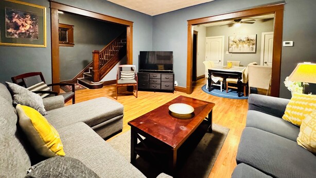 A living room with a sofa, a coffee table, a TV, and a staircase leading to another room. - Rainbow Inn on the Walnut Avenue ,  3bed room, 2full bath, double parking, WiFi  (Niagara Falls)