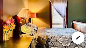 A hotel room with a bed, a desk, a lamp, and a vase of flowers. - Rainbow Inn on the Walnut Avenue ,  3bed room, 2full bath, double parking, WiFi  (Niagara Falls)