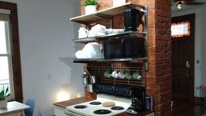 A compact kitchen with a brick accent wall, a stove, a microwave, and a sink. - Great views in OTR, lots of parking & big yard! (Cincinnati)