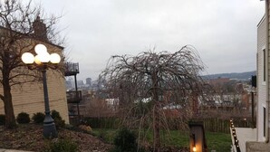 A residential area with a paved pathway, a street lamp, and a view of a cityscape in the background. - Great views in OTR, lots of parking & big yard! (Cincinnati)