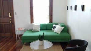 A living room with a green sofa, a round coffee table, a black chair, and a wooden floor. - Great views in OTR, lots of parking & big yard! (Cincinnati)