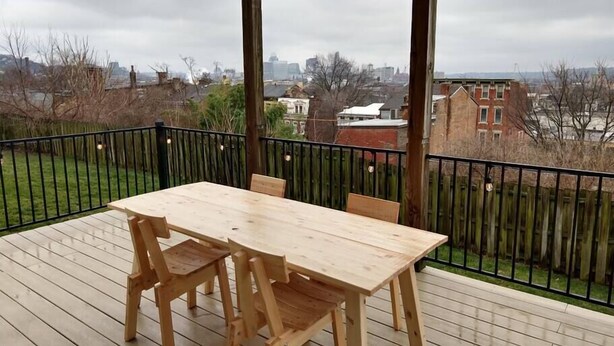 A wooden deck with a table and chairs, overlooking a grassy area and a cityscape. - Great views in OTR, lots of parking & big yard! (Cincinnati)