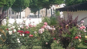 Un jardin où l’on trouve différentes sortes de fleurs et un bâtiment dont le toit est recouvert de tuiles.