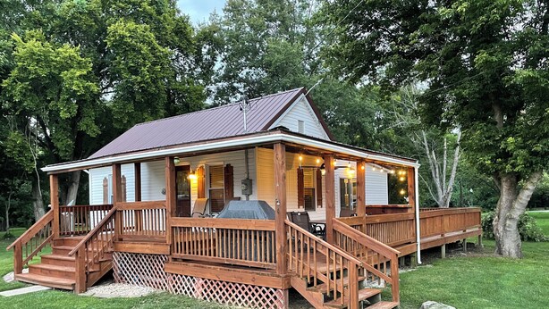 A wooden cabin with a porch, outdoor seating, and a grill. - Confluence Cabin Grafton, IL (Grafton)