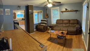 A living room with a brown leather sofa, a wooden coffee table, and a guitar wall decoration. - Confluence Cabin Grafton, IL (Grafton)