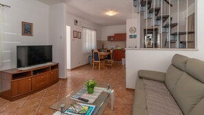 Una sala de estar con televisión, sofá y comedor con sillas y mesa.