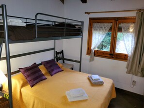 Cozy retreat with a bunk bed setup, chair, and window with lace curtains.