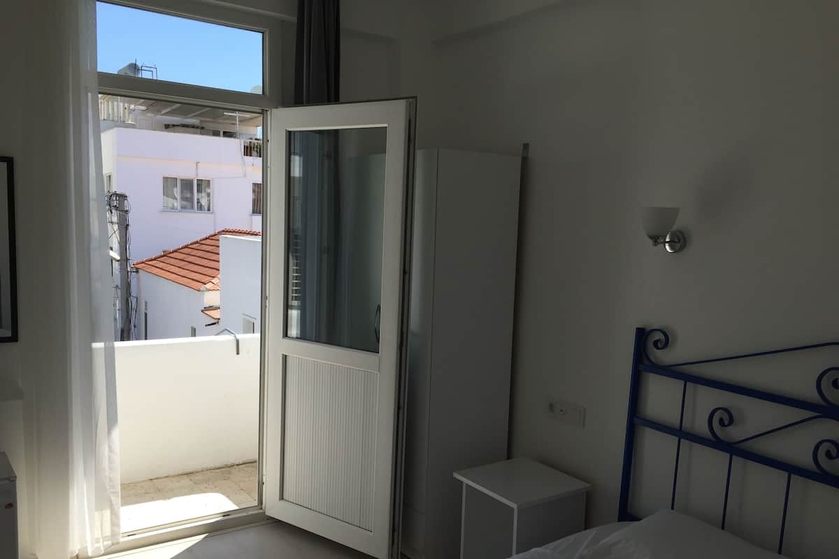 A bedroom with a bed, a nightstand, a wardrobe, and a window.