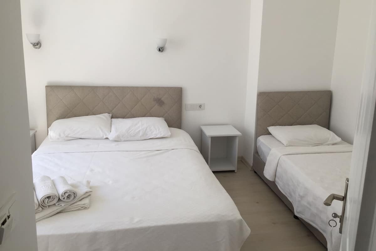 A hotel room with two beds, a bedside table, and a wall-mounted light fixture.