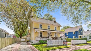 A two-story house with a porch, a picket fence, and a well-maintained lawn. - Sea Horse Cottage-5 Bedrooms, 3 Full Baths, 2 Half Baths, Sleeps 14 (West Cape May)